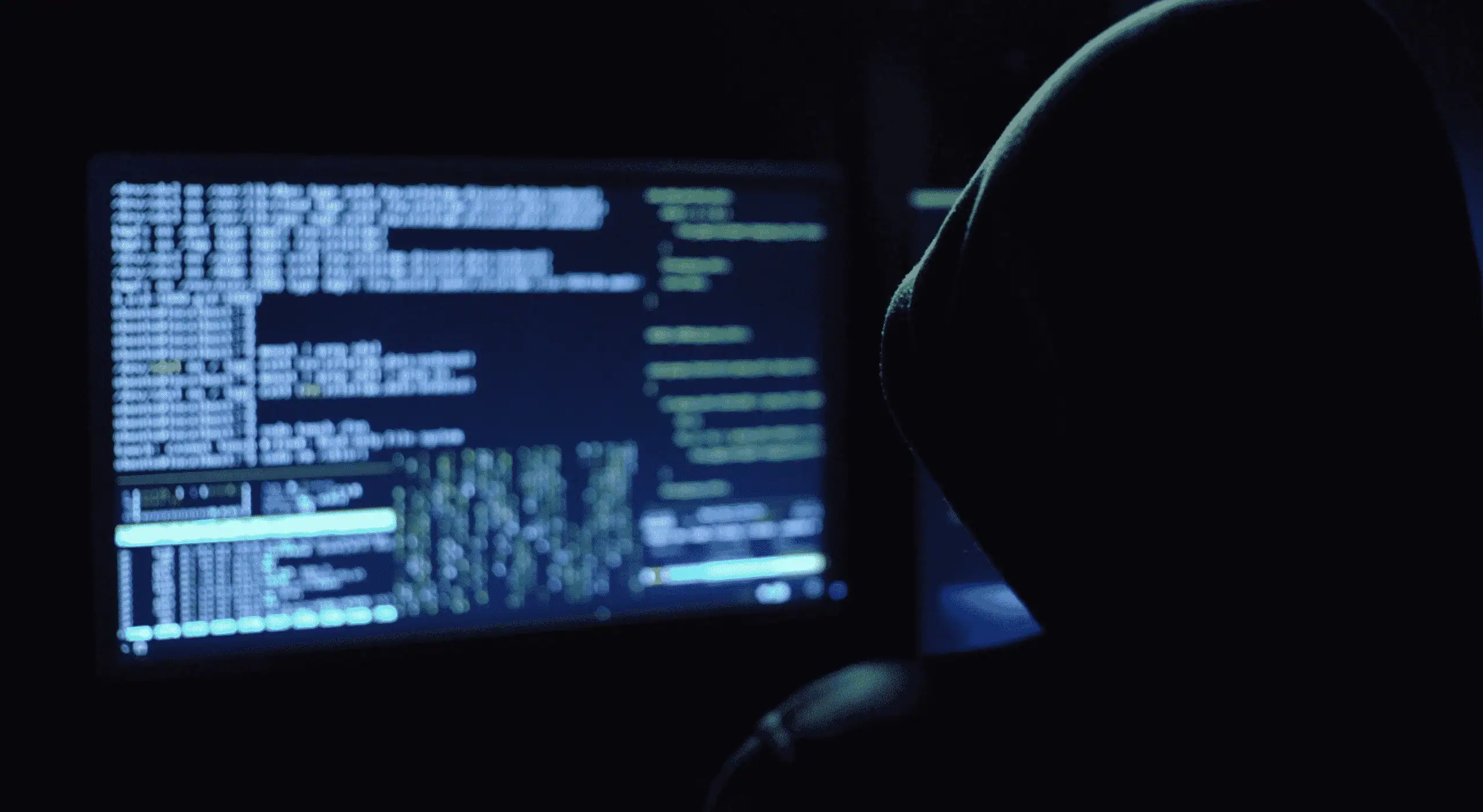 Hacker in dark hoodie working on computer with code on screen cybersecurity training at MyComputerCareer cybersecurity career education and skills development in IT and hacking techniques.
