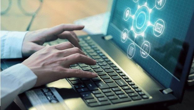 Hands typing on a laptop with digital network icons on the screen, representing technology education and IT training at MyComputerCareer.