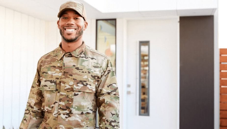 Veteran in camouflage military uniform standing outside a modern building, promoting career training programs in information technology and cybersecurity at MyComputerCareer.
