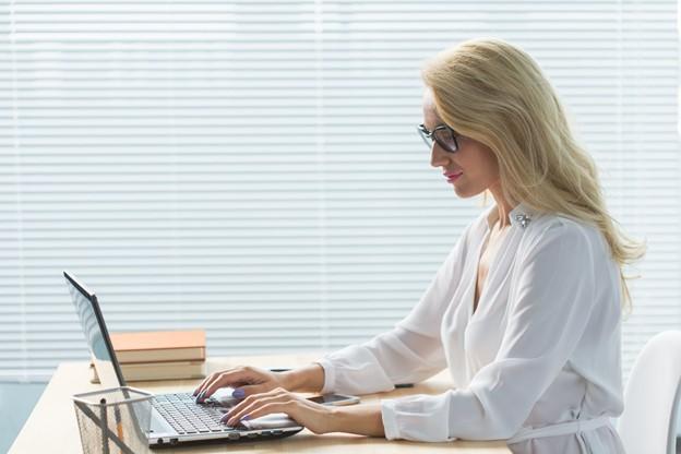 Laptop user studying computer career training at a modern office.
