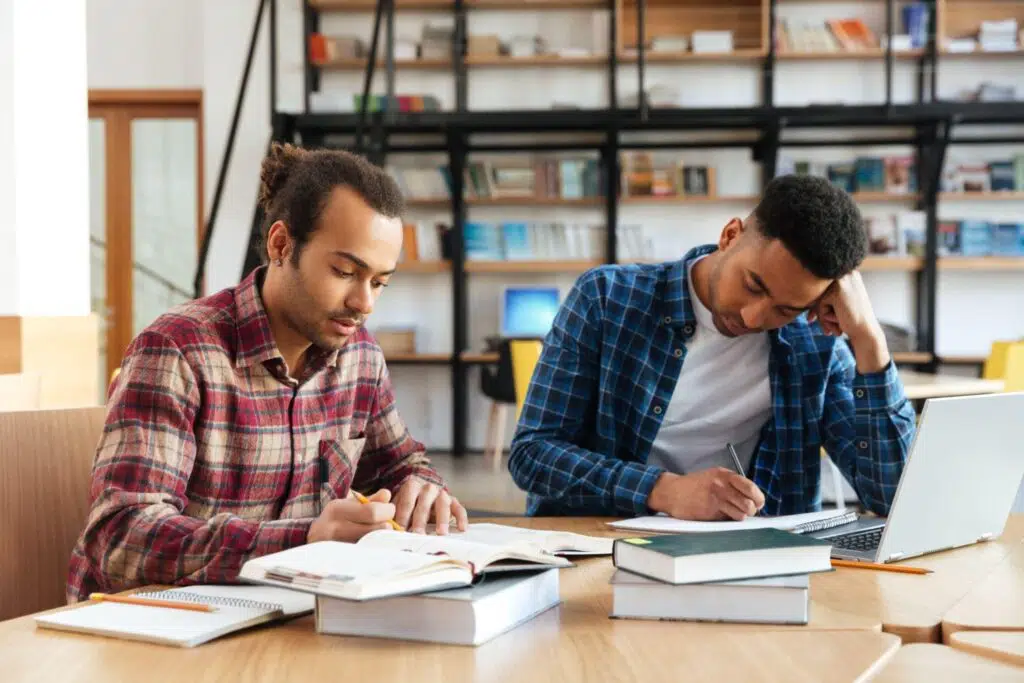 two-multicultural-male-students-studying-with-lapt-PHM4T66