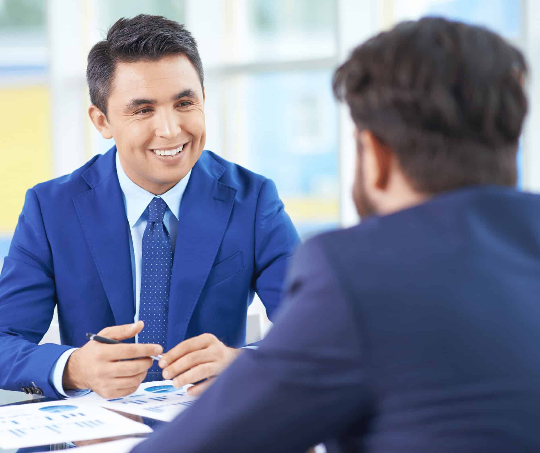 Professional man in blue suit discussing with a client at a career training center, emphasizing IT certification and tech career opportunities.