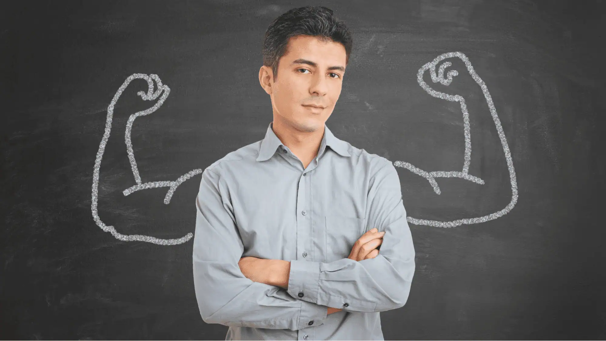 Strong man with arms crossed in front of chalkboard with drawn muscular arms, representing strength and confidence in IT career training programs at MyComputerCareer.