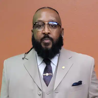 Man in beige suit with glasses and beard