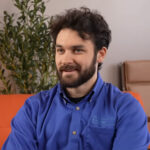 Bearded man in blue shirt sitting indoors