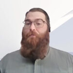 Bearded man with glasses speaking indoors