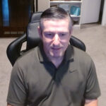 Man in green polo sitting at desk