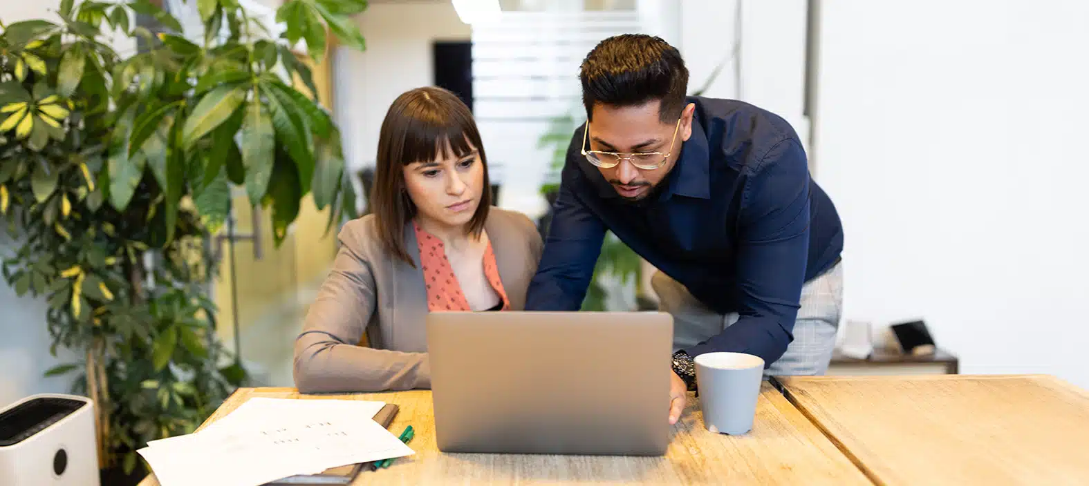 Two coworkers reviewing a laptop at an office table