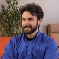 Bearded man in blue shirt sitting indoors