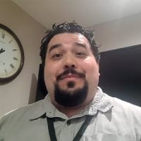 Man smiling indoors with wall clock behind